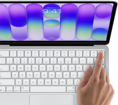 MacBook Neo, Farbe Silber, Anmeldebildschirm, ein Finger berührt den Touch ID Sensor oben rechts auf der Tastatur