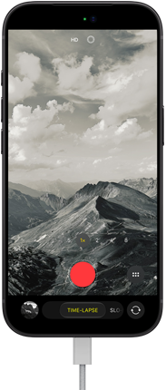 iPhone 18 Pro, Vorderseite, das Display zeigt eine Berglandschaft, mit der Kamera Modus Überlagerung im Zeitraffer Modus, mit dem Netzkabel am Ladeanschluss