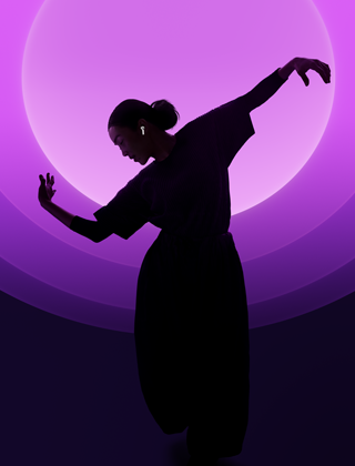 Eine Person mit den AirPods 5 beim Tanzen, mehrfarbiger Hintergrund